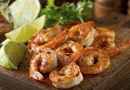 a pile of shrimp on a cutting board with lime slices at Pousada Roberto Monteiro - Frente Mar in Florianópolis