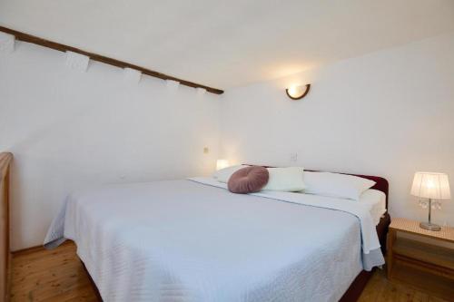 a white bed with white sheets and a brown hat on it at Festa Stradun Apartment in Dubrovnik