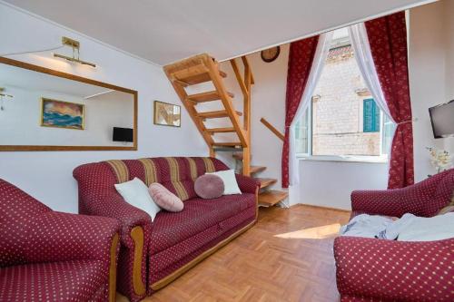 una sala de estar con 2 sofás rojos y una escalera en Festa Stradun Apartment en Dubrovnik