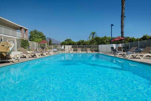 a large swimming pool with chairs and a volley ball court at Motel 6-Arcadia, CA - Los Angeles - Pasadena Area in Arcadia