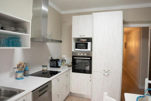 a kitchen with white cabinets and a stove top oven at Gallimó Apartaments in L'Ampolla