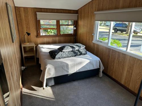a small room with a bed and a window at Patonga Holiday Home in Patonga