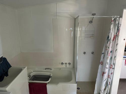 a white bathroom with a tub and a shower at Patonga Holiday Home in Patonga