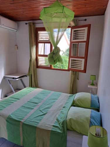 ein Schlafzimmer mit einem grünen Bett und einem Fenster in der Unterkunft MAISON de VACANCES ANSES D'ARLET in Les Anses-dʼArlets