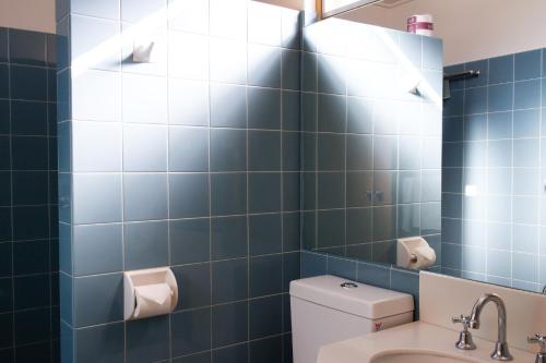 a blue tiled bathroom with a toilet and a sink at Mid City Motor Inn Queanbeyan in Queanbeyan