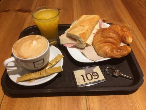un vassoio con un panino e una tazza di caffè e pasticcini di HOTEL BOUTIQUE DOÑA MANUELA a Tomelloso