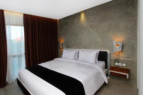 a large bed in a room with a large window at Greenhost Boutique Hotel Prawirotaman in Yogyakarta