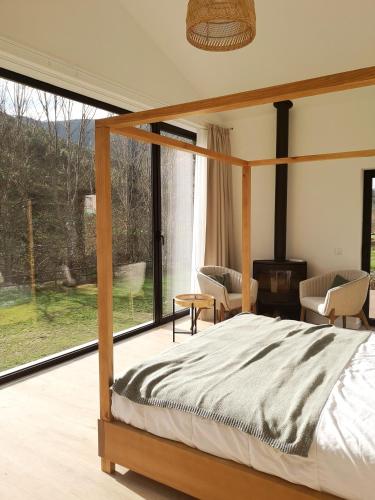 a bedroom with a canopy bed and a large window at Quinta das Levadas - Country House & Nature in Alvoco das Várzeas