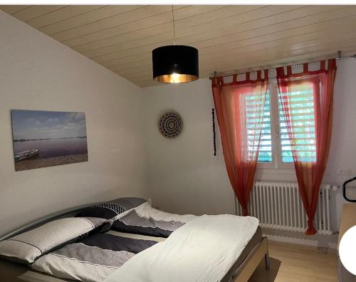 een slaapkamer met een bed en een raam met rode gordijnen bij Maison chez Louis in Asuel
