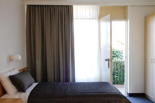 a bedroom with a bed and a large window at Mid City Motor Inn Queanbeyan in Queanbeyan