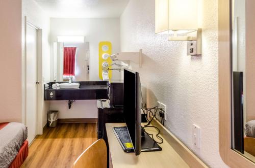 a room with a tv on a desk with a bathroom at North Charleston Lodge in Charleston