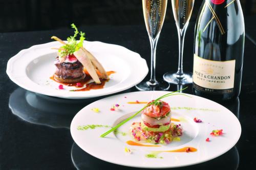 two plates of food on a table with a bottle of wine at Okazaki New Grand Hotel in Okazaki