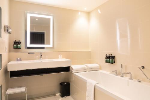 La salle de bains est pourvue d'un lavabo, d'une baignoire et d'un miroir. dans l'établissement Crowne Plaza Lyon - Cité Internationale, à Lyon