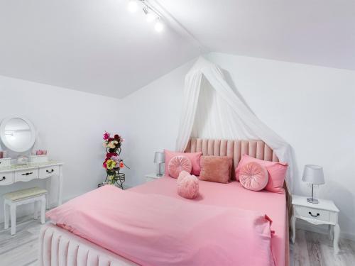 1 dormitorio con cama rosa y almohadas rosas en Consuela Residence, en Feleacu