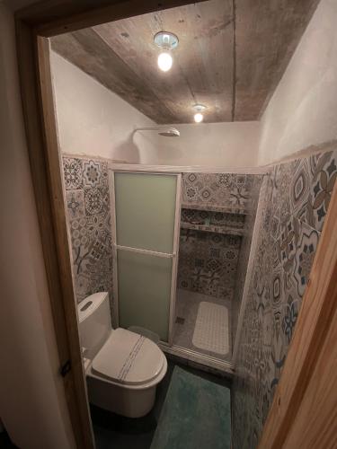 a small bathroom with a toilet and a shower at Hotel Maya Jade in Monterrico
