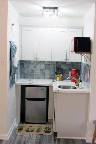 a small kitchen with white cabinets and a sink at Adorable Ground Level Boho Studio Blocks From Dwntn-C in Tempe