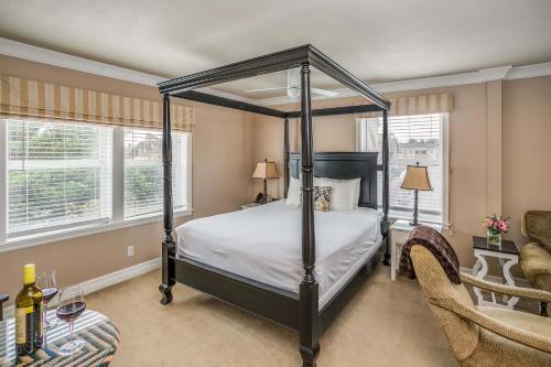 a bedroom with a four poster bed and two windows at Cannon Beach Hotel Collection in Cannon Beach