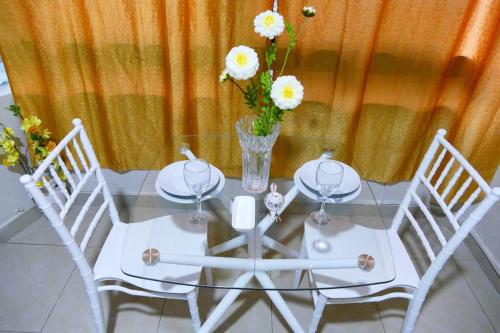 une table blanche avec deux chaises et un vase avec des fleurs dans l'établissement Suite Estudio D1 Alborada Riocentro Norte, à Guayaquil