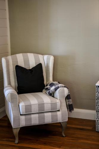 a striped chair with a black pillow on it at Tamworth Country Escape with a beautiful swimming pool! in Loomberah