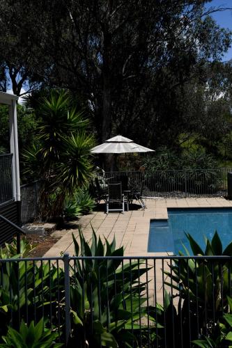 a swimming pool with an umbrella and a table and chairs at Tamworth Country Escape with a beautiful swimming pool! in Loomberah