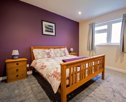 a bedroom with a wooden bed and a purple wall at Kilchrist Castle Cottages in Campbeltown