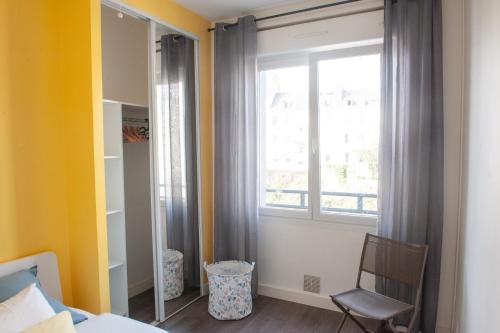 a bedroom with a bed and a window and a chair at Appartement spacieux avec balcon et parking in Brest