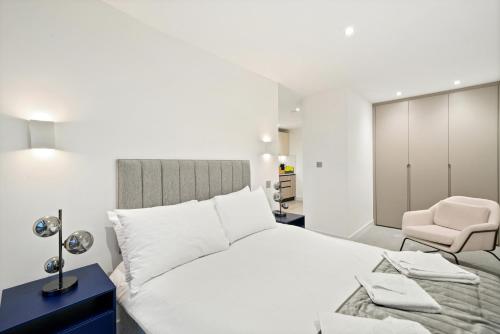 a white bedroom with a bed and a chair at Executive 1 & 2 Bed Apartments in heart of London FREE WIFI by City Stay Aparts London in London