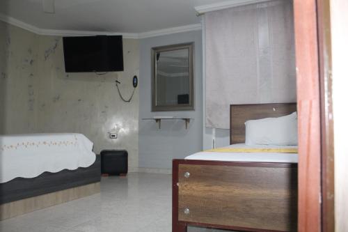 um quarto com uma cama e uma televisão na parede em HOTEL PRIMAVERA RIOHACHA em Ríohacha