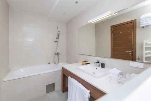 Un baño con lavabo, bañera y espejo. en Apartment B3-Aparthotel Vučko, en Jahorina