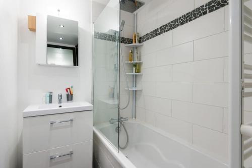 biała łazienka z prysznicem i umywalką w obiekcie Pied-à-terre cosy face aux pistes de La Princesse w mieście Demi-Quartier