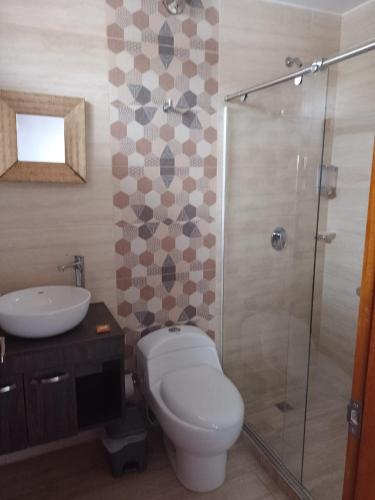 a bathroom with a toilet and a sink and a shower at Hotel Med Suites 94 in Barranquilla