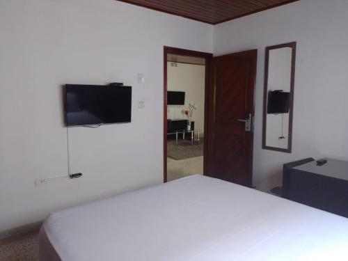 a bedroom with a white bed and a flat screen tv at Hotel Med Suites 94 in Barranquilla