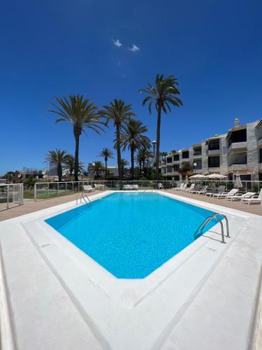 una piscina con palmeras en el fondo en San Agustin,close to the Beach with pool ! en San Bartolomé