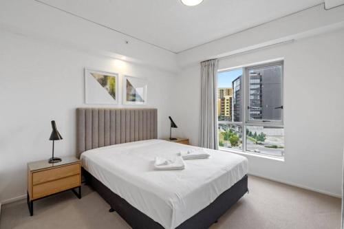 a white bedroom with a bed and a window at Lovely 2- Bedroom Rental Unit with Free Parking in Brisbane