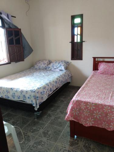 1 dormitorio con 2 camas y ventana en Refúgio sossego (casa de campo), en Camaçari