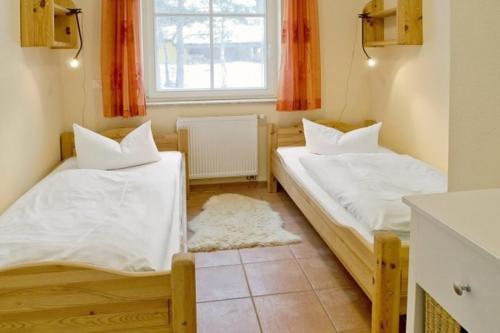 twee bedden in een kleine kamer met een raam bij Residenz am Haferland in Wieck