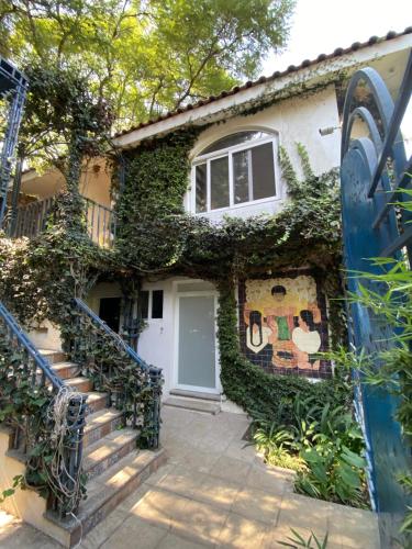 a house covered in ivy with a white door and stairs at Magnolias Jardin & Boutique Suites in León