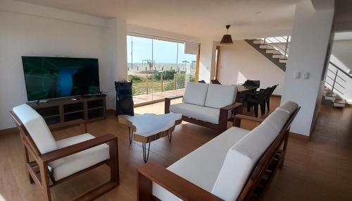 sala de estar con muebles blancos y TV de pantalla plana en CASA LUNA, en Chincha Baja