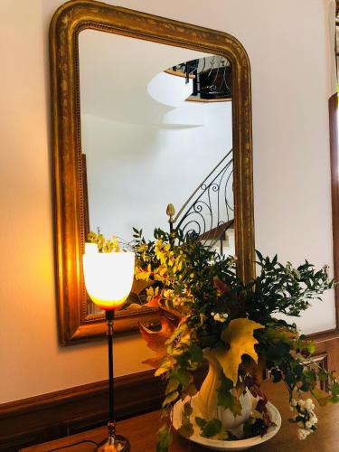 a table with a mirror and a vase with flowers at La plaine de l'Angelus in Chailly-en-Bière