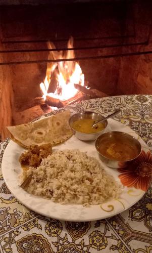 a plate of food on a table in front of a fire at Coorg Coffee Park Farmstay in Somvārpet