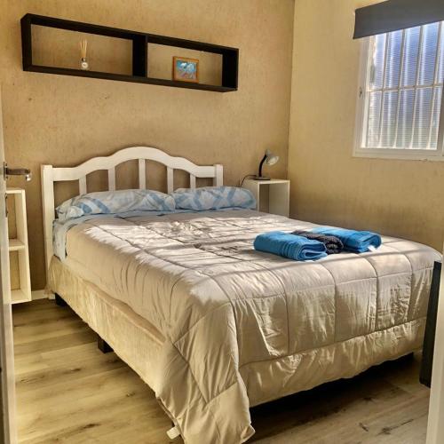a bedroom with a white bed with blue pillows on it at Esencia Cabaña in Potrerillos