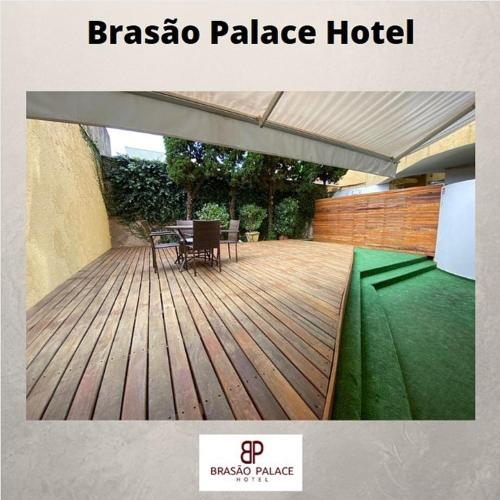 a wooden deck with a table and a green lawn at Brasao Palace Hotel in Presidente Prudente