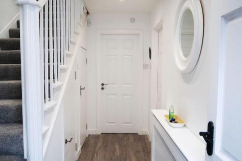 einen weißen Flur mit einer weißen Tür und einem runden Spiegel in der Unterkunft Central 2 bedroom luxury home close to River Ness in Inverness