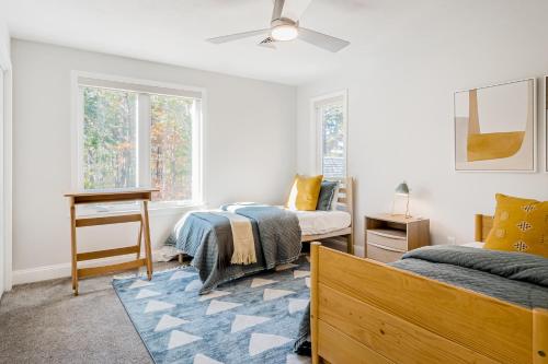 a bedroom with two beds and a desk and windows at Peace Among the Pines in Wellfleet