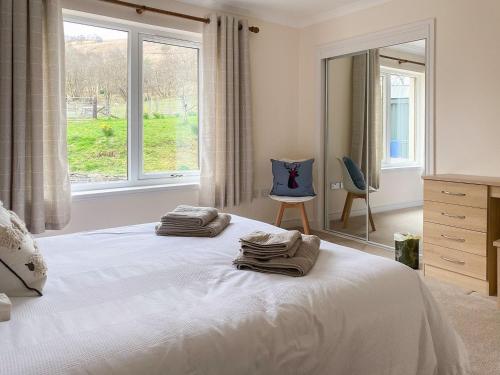 a bedroom with a bed and a window and a chair at Dalnafeidh Beag in Portnacroish