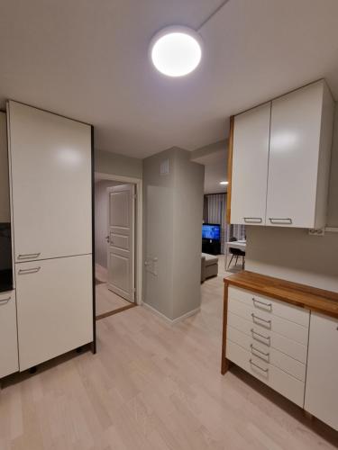 uma cozinha com armários brancos e uma sala de estar em Chausseen Apartment 
