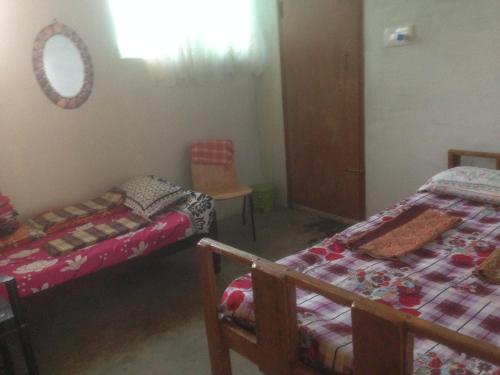 a room with two beds and a chair and a mirror at Holiyday in VGF Farm House in Dānishpet