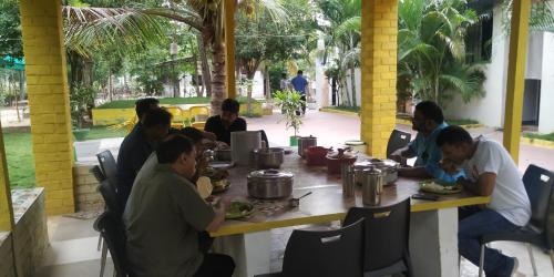 a group of people sitting around a table eating food at Holiyday in VGF Farm House in Dānishpet
