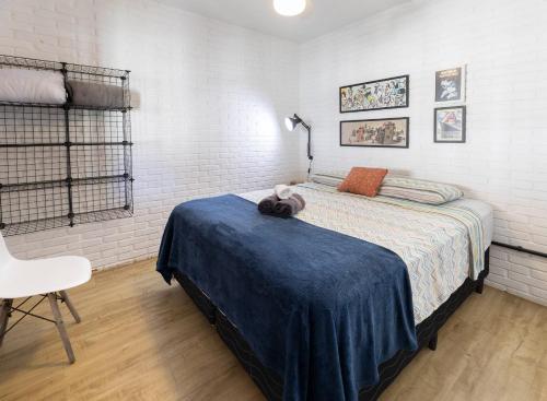 um quarto com uma cama com um cobertor azul e uma cadeira em Loft Califórnia em Bombinhas