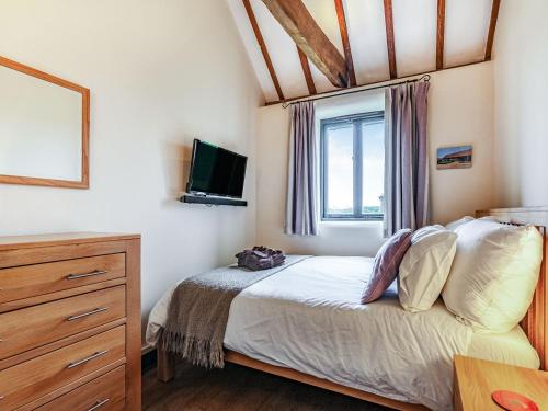a bedroom with a bed and a tv and a window at Flint Barn in Doddington